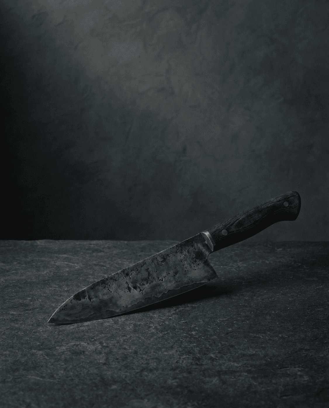 Hand-forged chef's knife resting on a dark stone surface